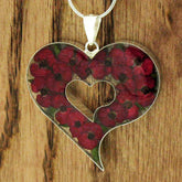 Heart-shaped necklace with real pressed red poppy on a wooden background
